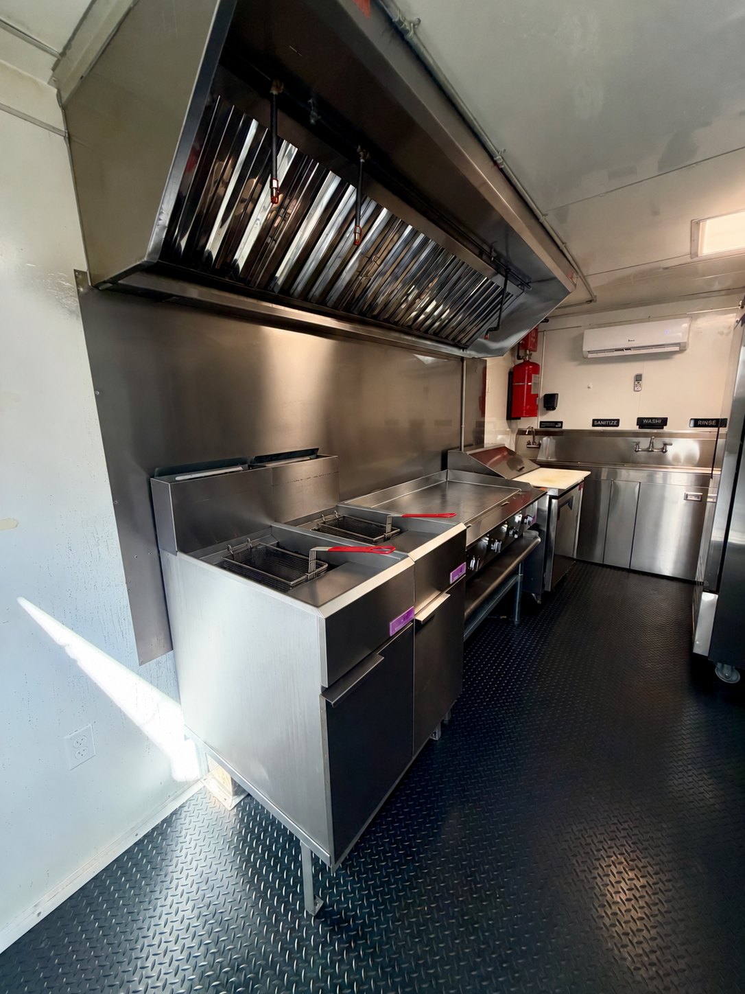 Pre-owned black 8.5 × 16 ft trailer — Kitchen cookline with two fryers and flat-top griddle