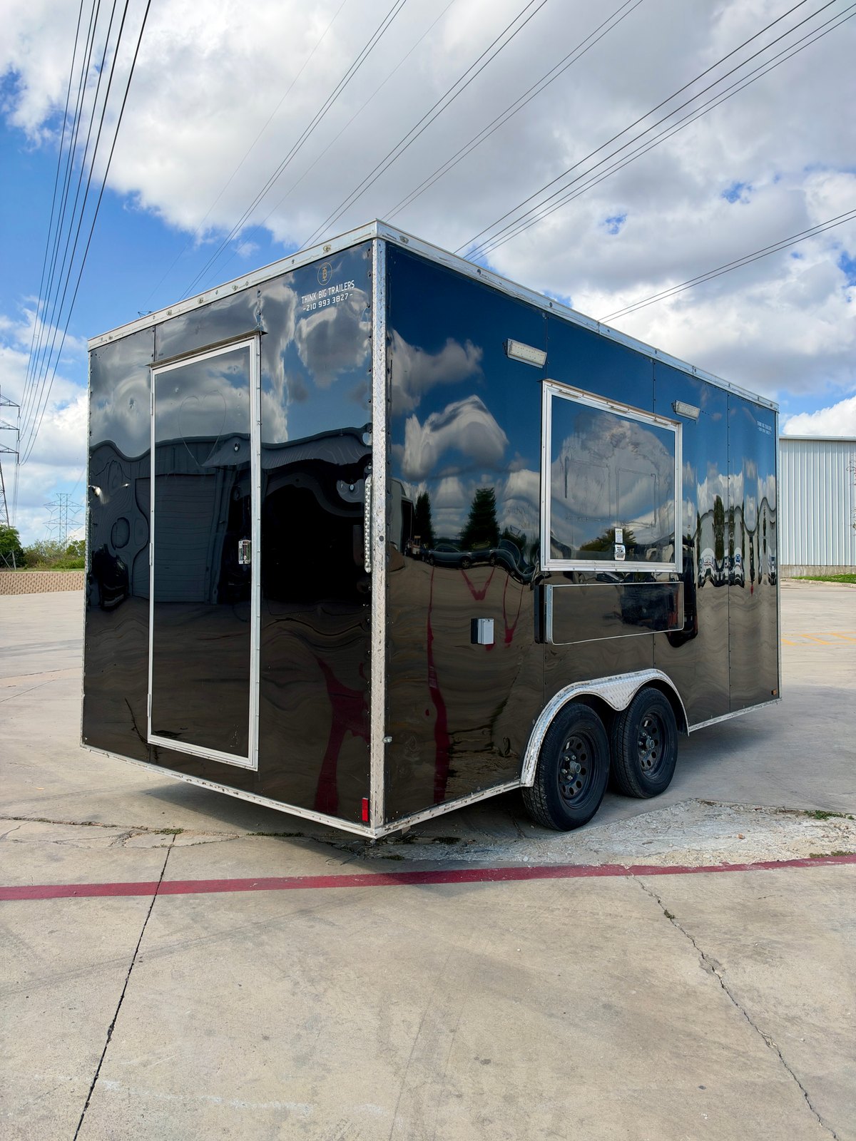 Pre-owned black 8.5 × 16 ft trailer — Rear and service-side exterior